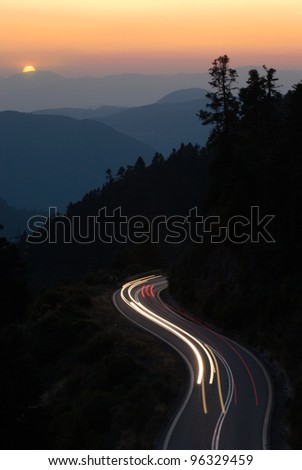Continental Greece light trails on a winding road of mountain at sunset