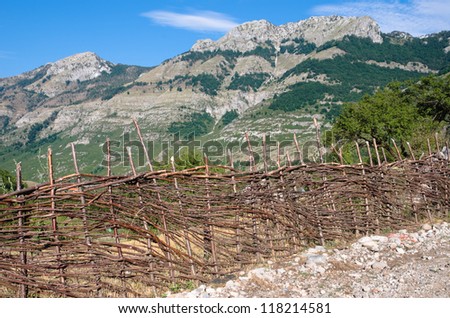 typical fence made of raw branches along a rural road between Boge and Theth, on the background peak albanian mountains