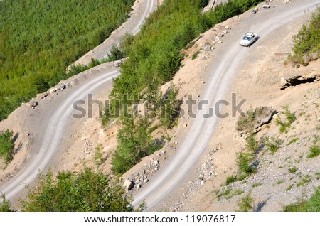 a old mercedes is traveling downhill on the winding dirt road into the Valley of the Kelmend between the albanian mountains