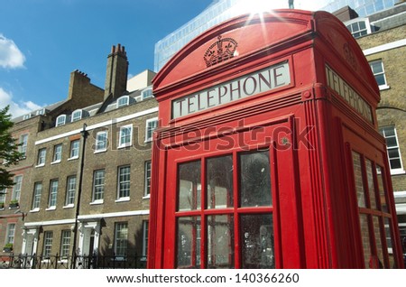 red phone booth in old style and typical brick building in London