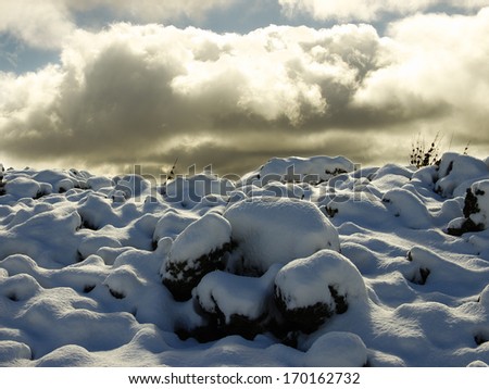 cold lava covered by snow on background clouds