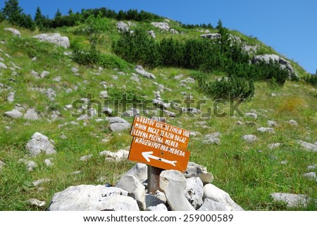 red sign on path of Durmitor National Park, Zabljak\
NOTE: in the sign there are proper names of mountain and cave in montenegrin language http://www.shutterstock.com/blog/images-with-non-english-text