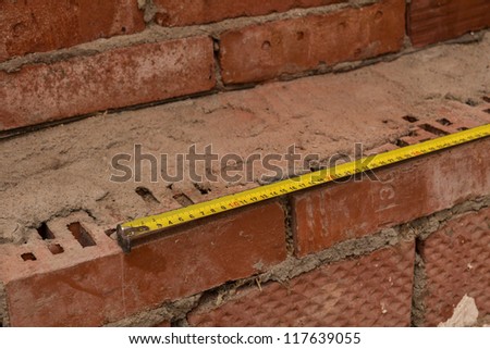 measuring brick wall with a yellow ruler