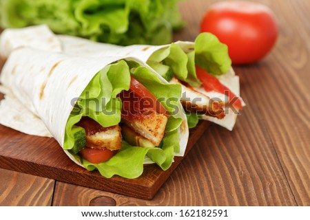 wheat tortilla with chicken and vegetables on wood board