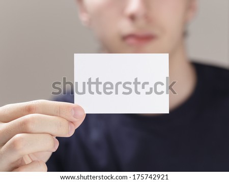 adult man hand holding empty business card in front of camera, blurred background