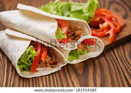 burrito with meat and ingredients on old wooden table rustic style