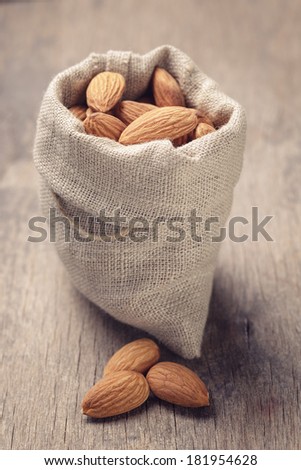 small sack bag full of almonds on wooden table, slightly toned in retro style