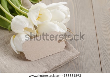 white tulips on wood table with label or note