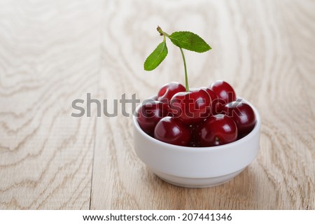 cherry berries in white bowl, on rustic oak table