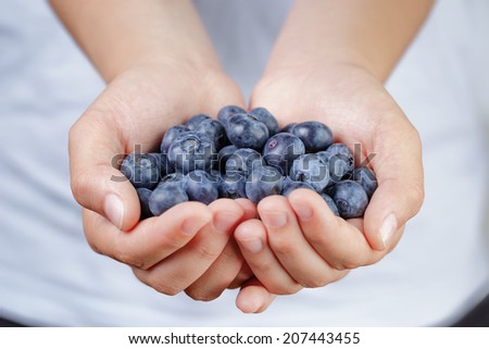 female teen hands holding ripe blueberries, shallow dof