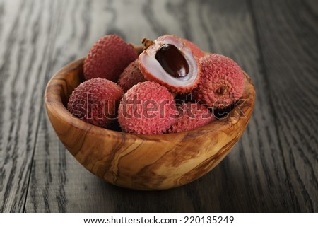 ripe lychees in wood bowl, on old oak table