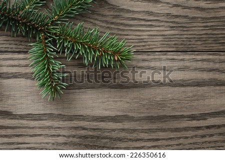 fir branch on stained oak table from above, christmas background