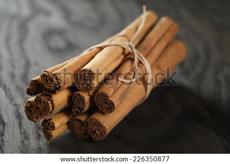 bunch of cinnamon sticks tied with twine, on rustic oak table