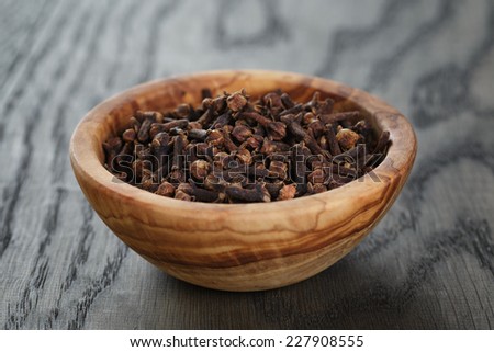 cloves in olive bowl on oak table, christmas spice