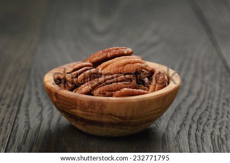 pecan nuts in olive wood bowl on oak table, rustic style