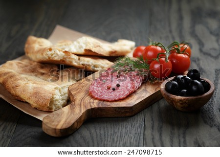 Antipasti with salami, olives, tomatoes and bread on wod table