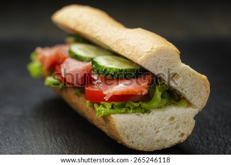 sandwich with salmon and vegetables on slate background