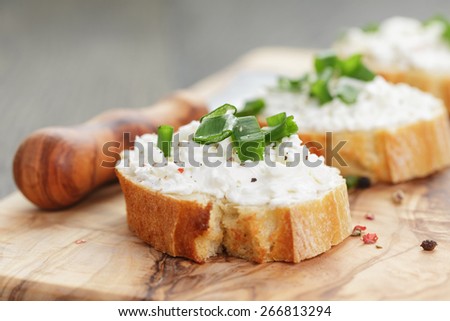 crunchy baguette slices with cream cheese and green onion on olive board