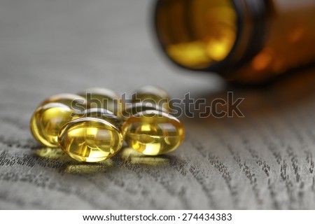 fish oil capsules with bottle on wooden table