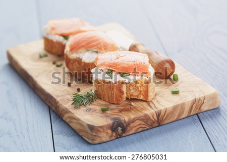 small sandwiches with soft cheese and salmon on wood table
