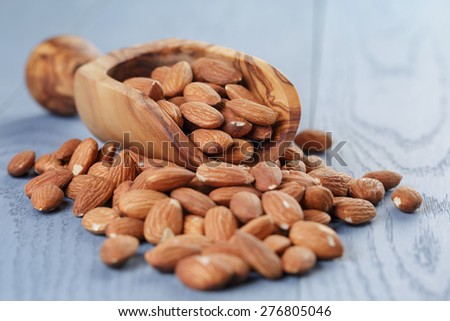 roasted almonds in measuring scoop on blue wooden table