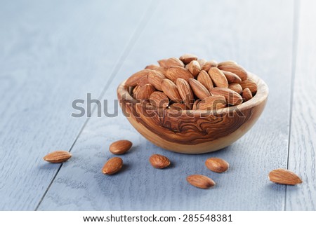 roasted almonds in bowl on blue wooden table, shallow focus
