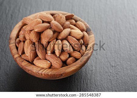 roasted almonds in bowl on slate background, shallow focus