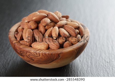 roasted almonds in bowl on slate background, shallow focus