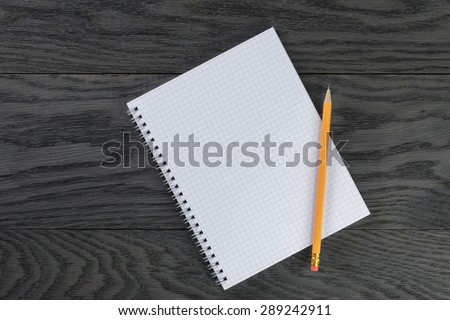 blank notepad with chequered pages on gray wood table and pencil, top view