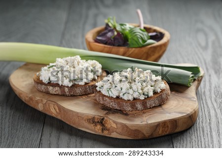 rye sandwiches or bruschetta with ricotta cheese and herbs on wooden table