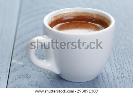cup of fresh espresso on vintage blue table close up