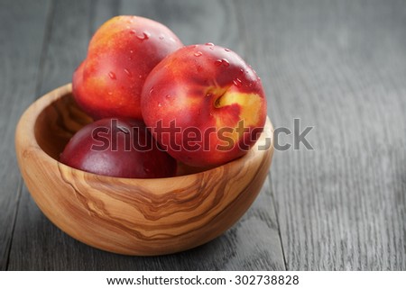 nectarines in olive wood bowl on oak table, shallow focus