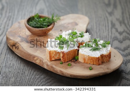 crunchy baguette slices with cream cheese and herbs on olive board