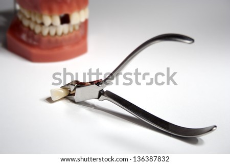 Artificial jaw with missing tooth and dentistry tongs