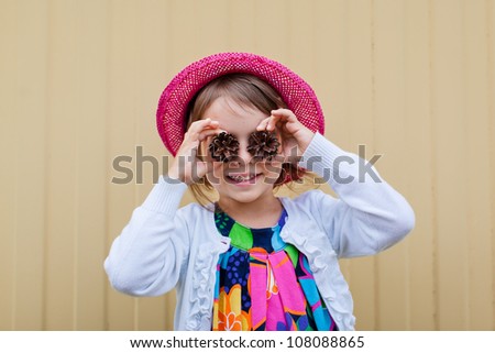 Adorable toddler girl covering her eyes with cones