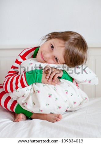Adorable toddler girl in pajamas hugging her pillow