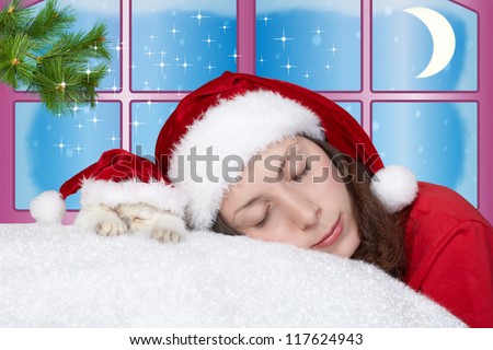 Young girl and little cat wearing Santa\'s hat sleeping