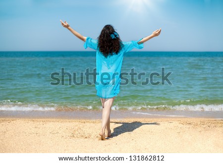 Young happy woman stretches out his hands to the sky with sun back to camera