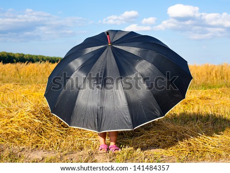 Little girl hiding under big black umbrella in fair weather