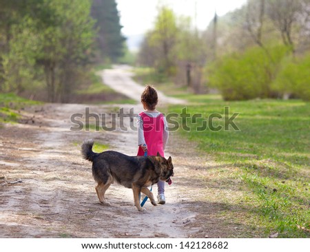 Little girl with dog on the road back to camera