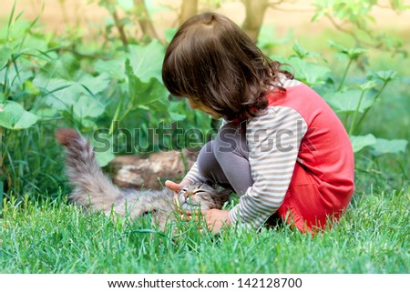 Little girl playing with cat on the grass