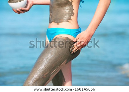 Woman smearing mud mask on the body