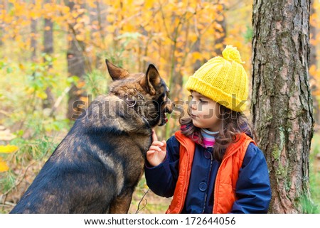 Little girl with big dog looking at each other in the forest in autumn
