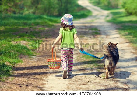 Little girl walking with dog back to camera