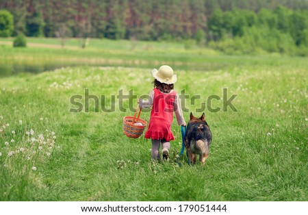 Little girl walking and going to picnic with dog back to camera
