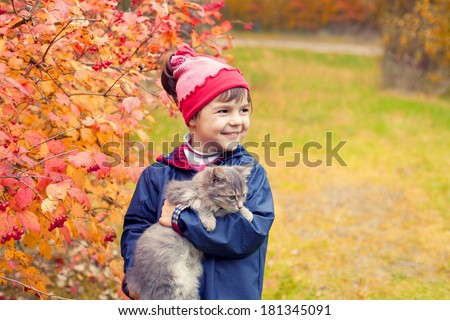 Little girl hugging a cat in the garden in autumn