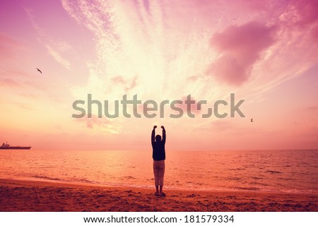 Silhouette of man raised his hands to the sky at sunset. Marsala warm color