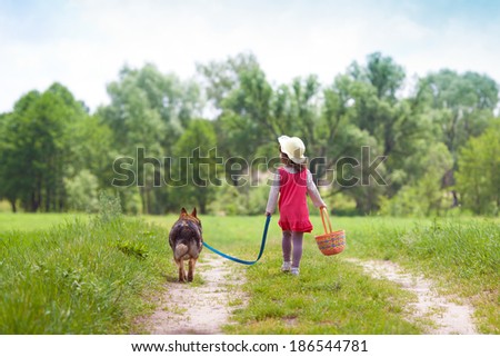 Little girl with dog running on the road to the picnic
