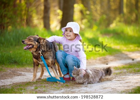 Little girl with big dog and cat in the forest