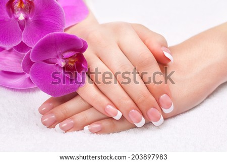 Beautiful woman\'s hands with perfect french manicure near purple orchid flowers